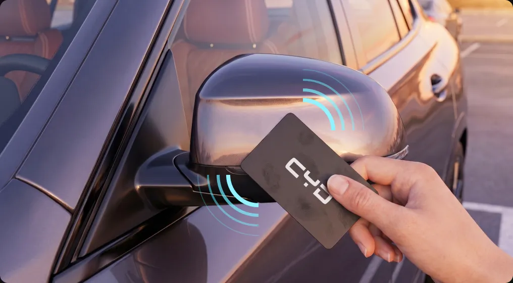A hand holding a CYD NFC card up to the sensor area on a car wing mirror